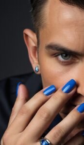 image focused on a closeup of males blue color nail polish